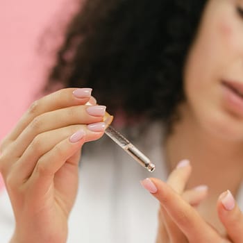 close up of woman putting serum on her finger with the use of a pipette