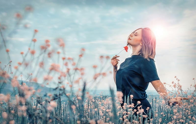 Mujer disfrutando del aroma de las flores del verano