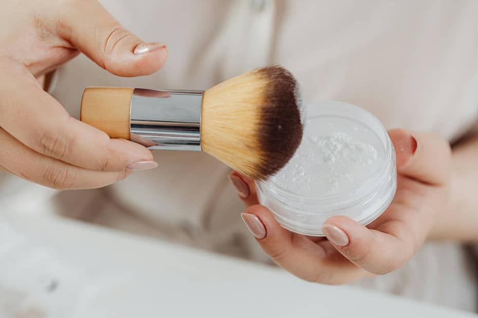 a person holding a makeup brush and face powder