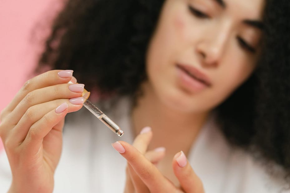 close up of woman putting serum on her finger with the use of a pipette