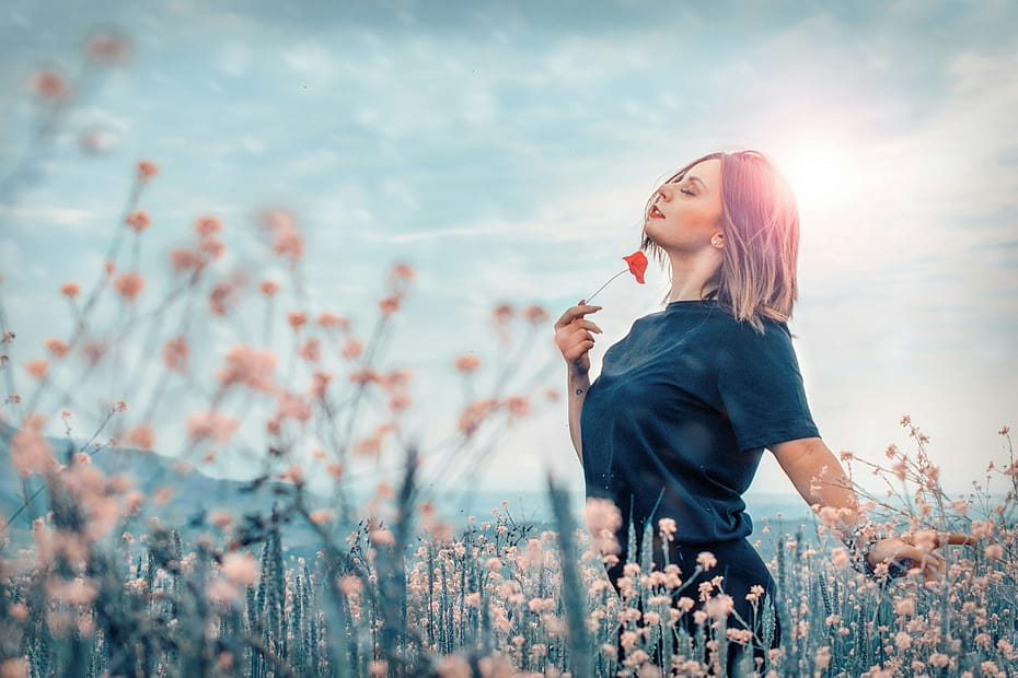 Mujer disfrutando del aroma de las flores del verano