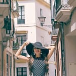 stylish woman in hat on street between buildings